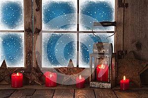 Christmas window with red burning candles and a lantern for a ba