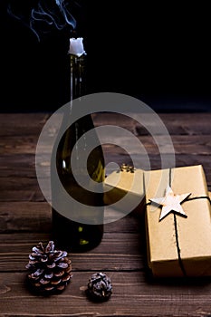 Christmas wine bottle candle with gifts on wooden table