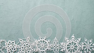 Christmas or winter background blue rough crafts paper with handmade crochet snowflakes.