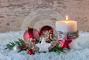 Christmas winter decoration with burning candle on snow and wooden background