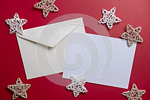 Christmas winter festive ornament. Blank paper card and envelope with wooden decoration on red background. Minimal decoration.