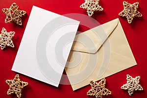 Christmas winter festive ornament. Blank paper card and envelope with wooden decoration on red background. Minimal decoration.