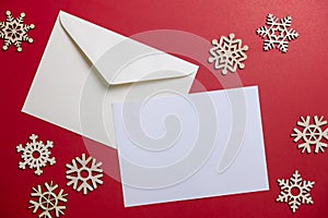 Christmas winter festive ornament. Blank paper card and envelope with wooden snowflake on red background. Minimal decoration.