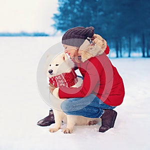 Christmas, winter and people concept - happy woman owner embracing white Samoyed dog outdoors