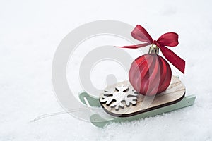 Christmas winter wooden sleigh with red bauble over the snow. Abstract winter greeting card with copy space