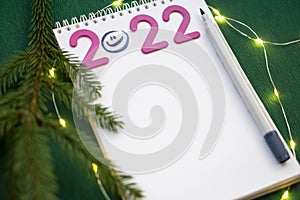 Christmas wishlist 2022 or letter to Santa on green colored paper background. Festive decoration, Christmas garland