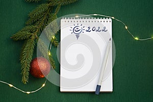 Christmas wishlist 2022 or letter to Santa on green colored paper background. Festive decoration, Christmas garland