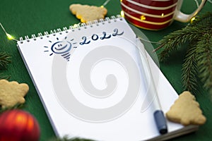 Christmas wishlist 2022 or letter to Santa on green colored paper background. Festive decoration, Christmas garland