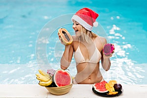 Christmas woman beautiful smiling in Santa`s hat with a tropical fruits
