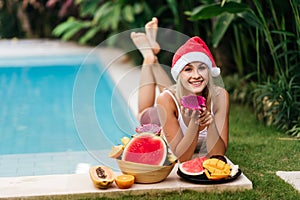 Christmas woman beautiful smiling in Santa`s hat with a tropical fruits