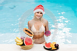 Christmas woman beautiful smiling in Santa`s hat with a tropical fruits