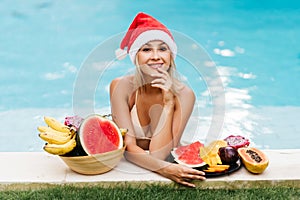 Christmas woman beautiful smiling in Santa`s hat with a tropical fruits