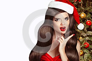 Christmas Woman. Brunette Girl in Santa Hat with red lips isolated on white Background. Funny Laughing Surprised Woman Portrait.