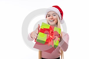 Christmas woman holding giving gift excited pointing. Happy smiling woman in santa hat giving you a present being joyful, fresh an