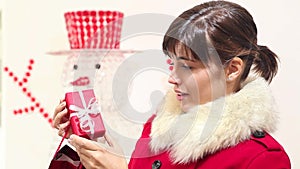 Christmas woman opens bag with gift and smiles, snowman in the background