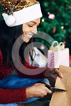 Christmas, woman and scissors for cutting paper to wrap gift in home. Xmas spirit, holiday and happy female from India
