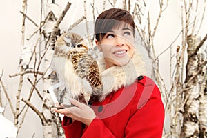 Christmas woman smiling with owl toy decoration, looks up on trees background