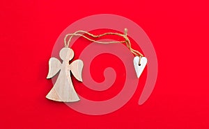 Christmas wooden angel with heart and twine on bright red background. Minimalism concept.