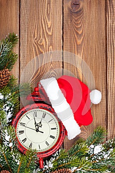 Christmas wooden background with clock, fir tree and santa hat