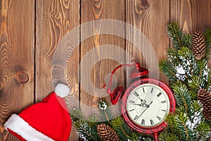Christmas wooden background with clock, santa hat and snow fir t