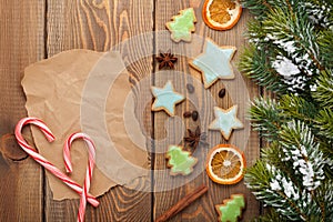 Christmas wooden background with snow fir tree, spices, gingerbr