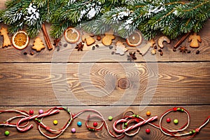 Christmas wooden background with snow fir tree, spices and gingerbread cookies