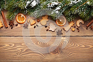 Christmas wooden background with snow fir tree, spices and gingerbread cookies