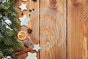 Christmas wooden background with snow fir tree, spices and gingerbread cookies