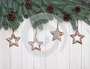 Christmas wooden background with tree branches, pine cones and stars