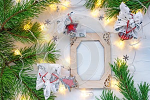 Christmas wooden frame decorated pine branches, fairy lights and present in furoshiki style