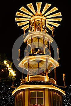 Christmas wooden pyramid rotates with nativity scene, people walking during Christmas market, German Night street Xmas and holiday