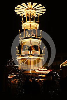 Christmas wooden pyramid rotates with nativity scene, people walking during Christmas market, German Night street Xmas and holiday