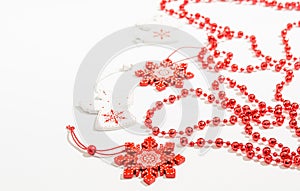 Christmas wooden toys in the form of a white angel and a red snowflake with bright red beads on a white background