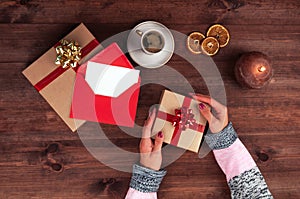 Christmas workplace top view. GirlÃ¢â¬â¢s hands on the wooden table holding Christmas preset. Christmas wreath, decorations photo