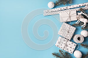 Christmas wrapping white gifts with decor branches on blue background. Flat lay. Top view.