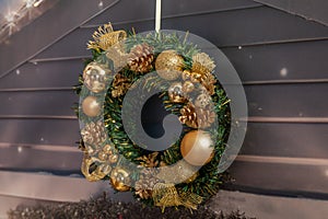 Christmas wreath against white wooden wall with golden ornaments