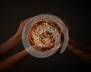 Christmas wreath of branches with yellow garlands. hold hands of man and woman with tattoo around dark background