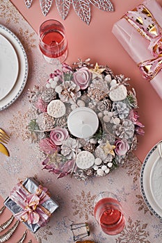 Christmas wreath with candle centered on a table served for holiday dinner, top view