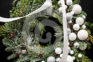 Christmas wreath decorated with white ribbon, white balls of different sizes close-up