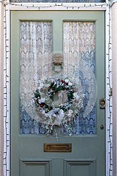 A Christmas wreath decoration hanging on the front door of a home