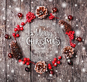 Christmas wreath of Fir branches, cones, red decorations on dark wooden background