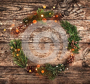 Christmas wreath of Fir branches, pine cones, berries and red ribbon on wooden background