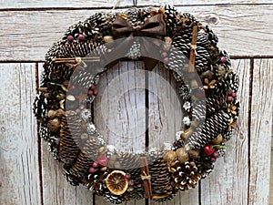 Christmas wreath of fir cones, nuts, berries, brown on a beige plank background
