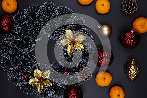 Christmas wreath, fir tree decor and tangerines on black background. Winter Holiday season composition