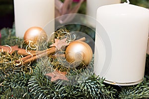 Christmas wreath from fresh green fir tree branches decorated with golden star ornaments baubles cinnamon sticks white candles