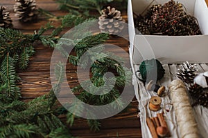 Christmas wreath, green branches, pine cones festive decorations, scissors, twine