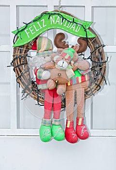 Christmas wreath hanging on the door with the inscription in Spanish - `Happy Christmas` Feliz Navidad