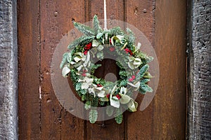 A Christmas wreath hanging on a rope on an old wooden front door