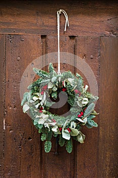 A Christmas wreath hanging on a rope on an old wooden front door