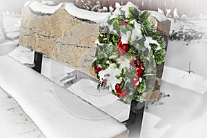 Christmas wreath hanging on a snow covered wooden bench